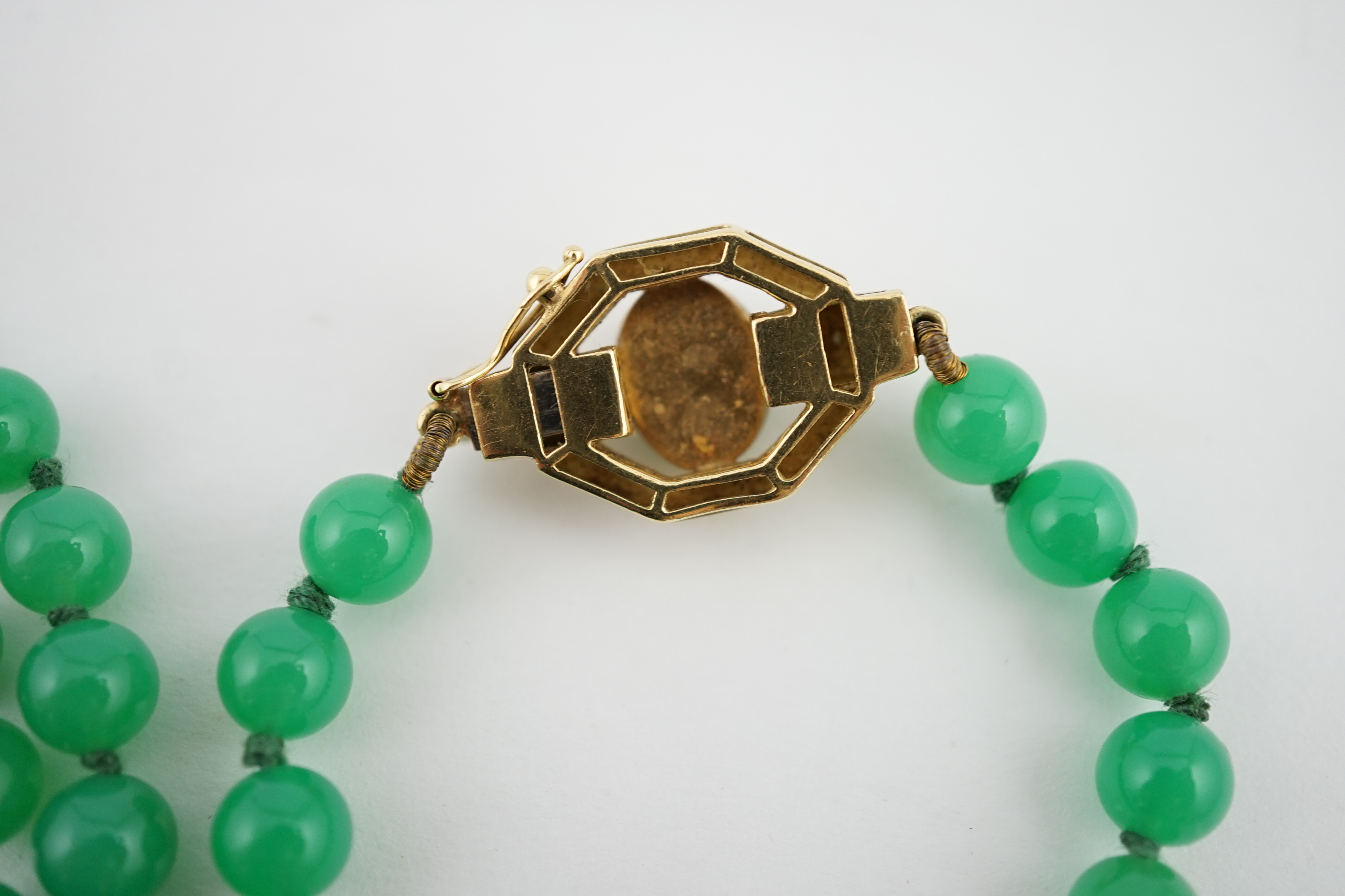 A modern long single strand jadeite bead necklace, with a cabochon jade and diamond chip cluster set 18k clasp